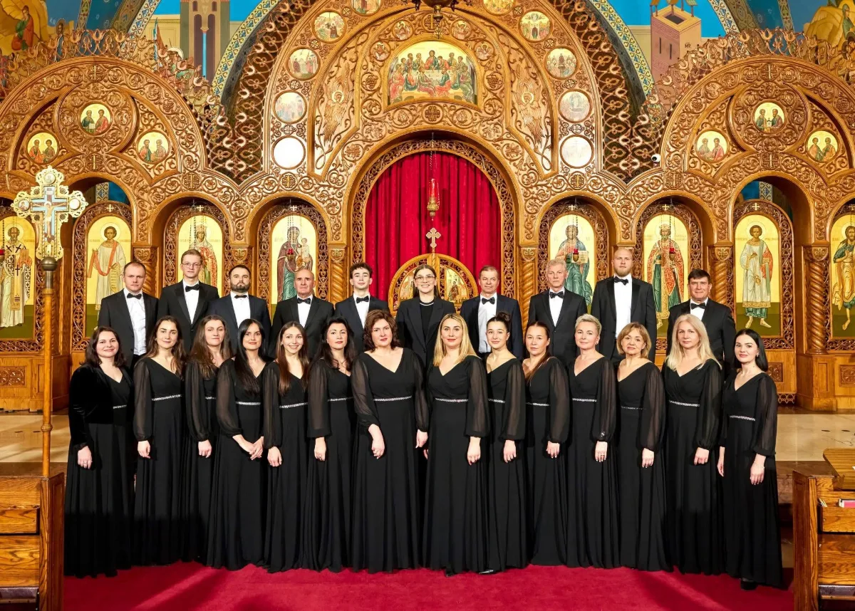 Choir Glorious, about two dozen singers in black concert dress, standing in two rows in front of a carved and gilded church iconostasis with a red curtain